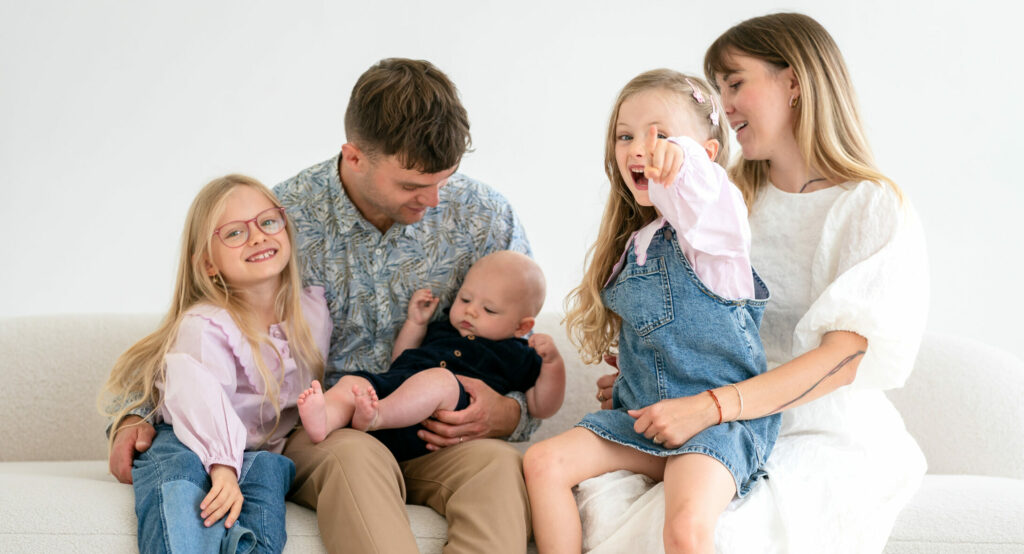 A happy family sitting together on a couch at home.